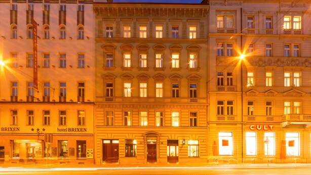 A row of historic buildings with illuminated signs, including a hotel named 'Brixen' and a store named 'CULT'. - S42 Hotel Prague (Prague)