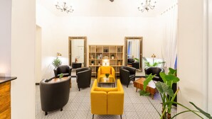 A modern living room with a yellow sofa, black armchairs, a coffee table, and a bookshelf. - S42 Hotel Prague (Prague)