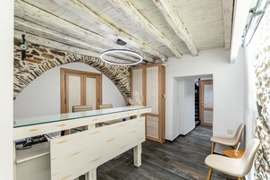 Una cocina moderna con encimera de vidrio, armarios de madera y una pared decorativa de piedra.