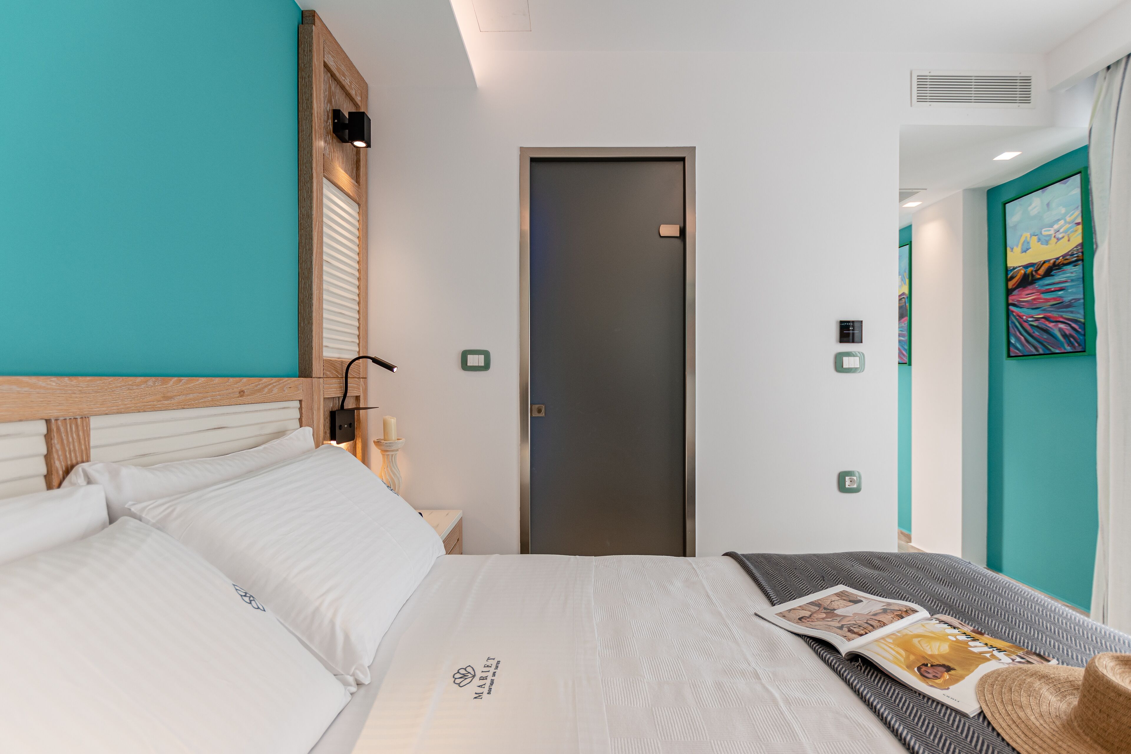 A neatly arranged hotel room with a bed, a nightstand, a door, and a wall with a painting.