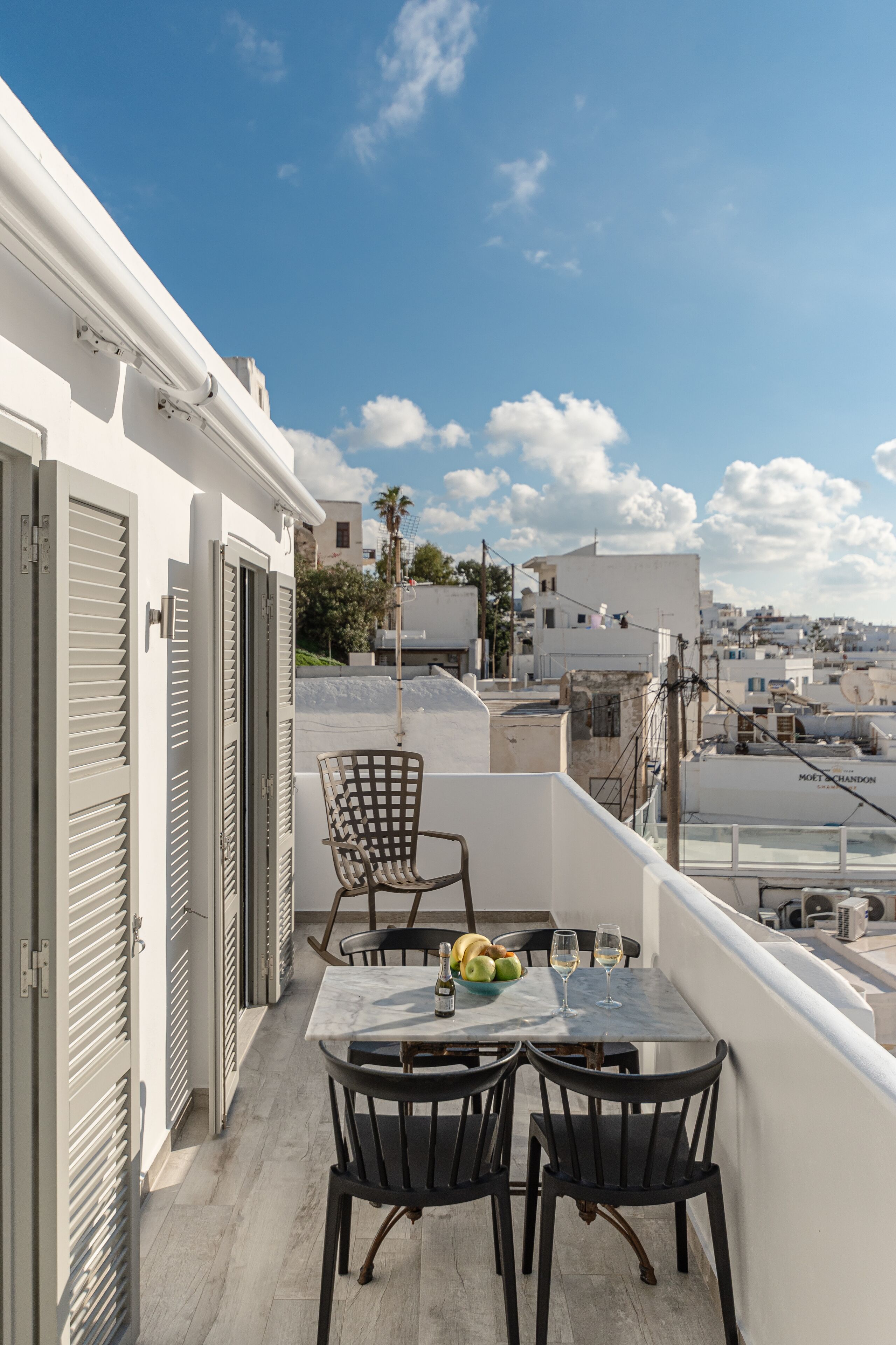 A balcony with a table, two chairs, and a bowl of fruit.