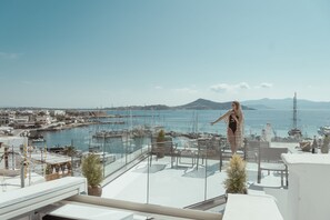 A terrace with a view of a marina, boats, and a distant mountain. - Mariet Naxos Elegant Suites (Naxos)