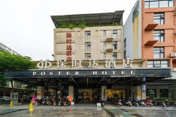 Das Poster Hotel mit moderner Fassade, einem überdachten Eingangsbereich und einer Reihe geparkter Roller.