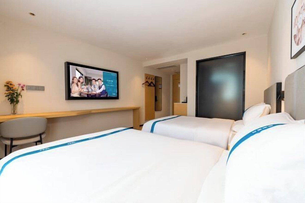 Ein Hotelzimmer mit zwei Betten, einem Schreibtisch, einem Fernseher und einer Tür.