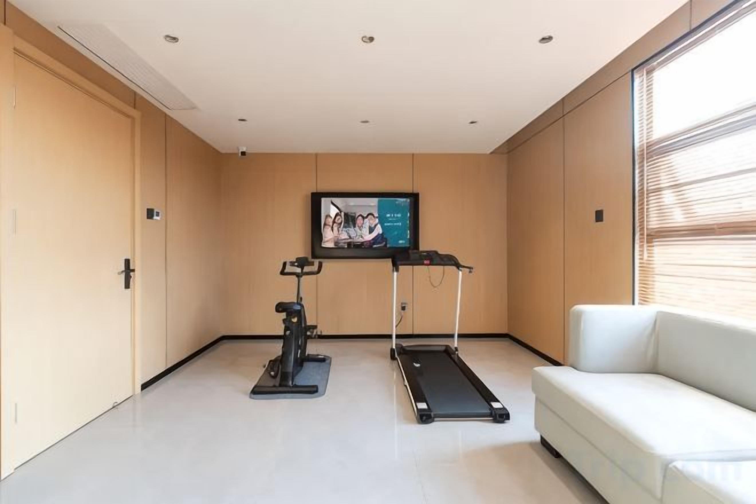 A room with a treadmill, stationary bike, and a TV on a stand.