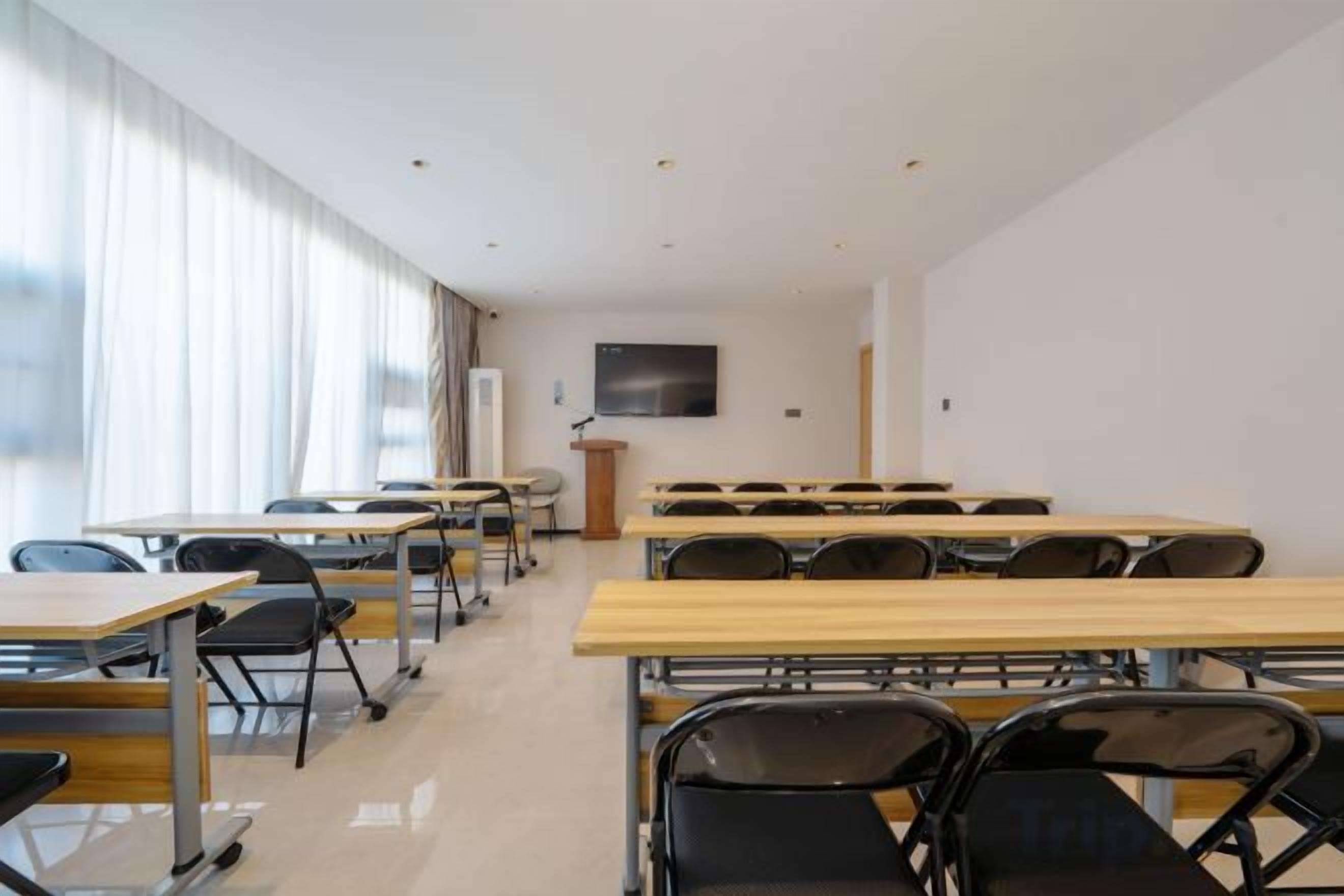A classroom with rows of desks and chairs, a podium, and a large window with curtains.