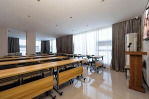 A conference room with multiple tables and chairs, a podium, and large windows with curtains. - GELI Hotel (Guigang High-speed Railway Station Shenghuogang) (Guigang)