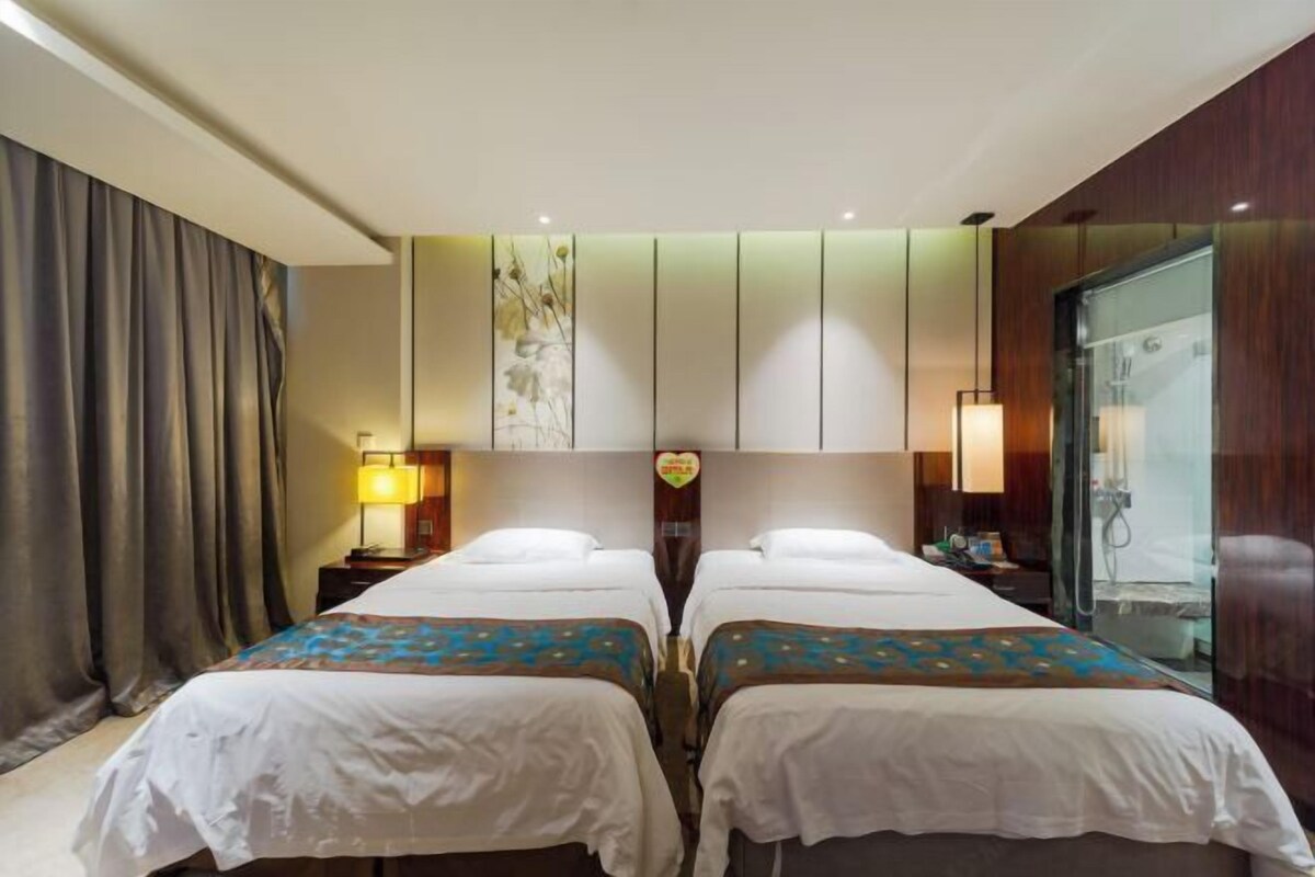 Ein Hotelzimmer mit zwei Betten, einem großen Fenster und einer Dusche.