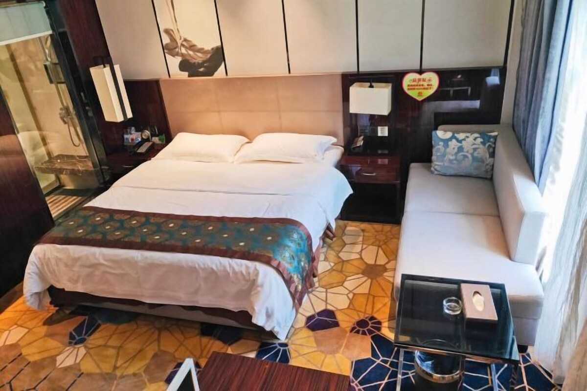 Ein Hotelzimmer mit einem großen Bett, einer Couch, einem kleinen Tisch und einer Duschkabine.