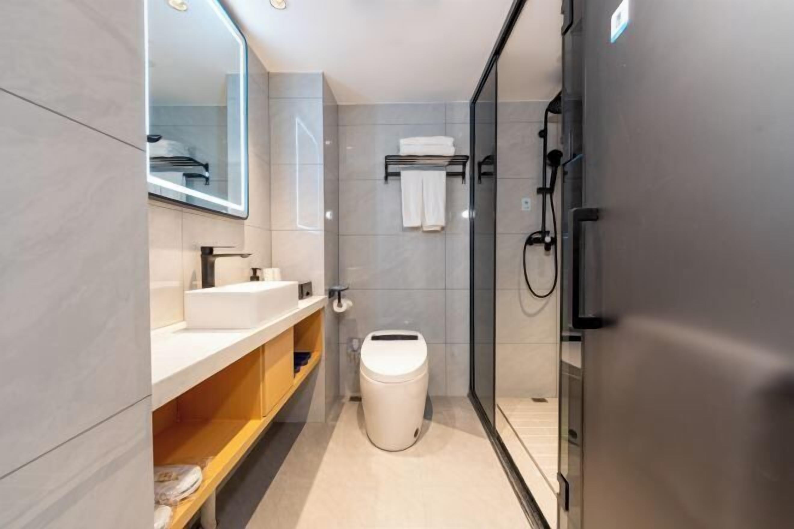Een moderne badkamer met een glazen douchecabine, een wit toilet en een wastafel met spiegel erboven.