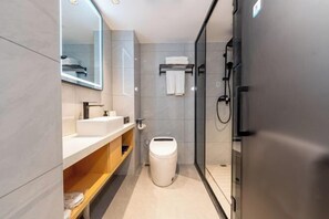 Ein modernes Badezimmer mit einer Duschkabine aus Glas, einer weißen Toilette und einem Waschbecken mit Spiegel darüber.