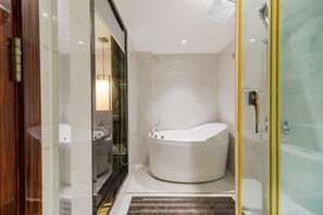 Ein modernes Badezimmer mit einer freistehenden Badewanne, einer Duschkabine aus Glas und einem sichtbaren Waschplatz.