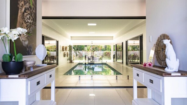A modern indoor pool area with a clear view of the pool, a reception desk, and a large window. - Luxury Tropical Escape: Beachside Villa with Heated Pool & Modern Comforts (Trinity Beach)