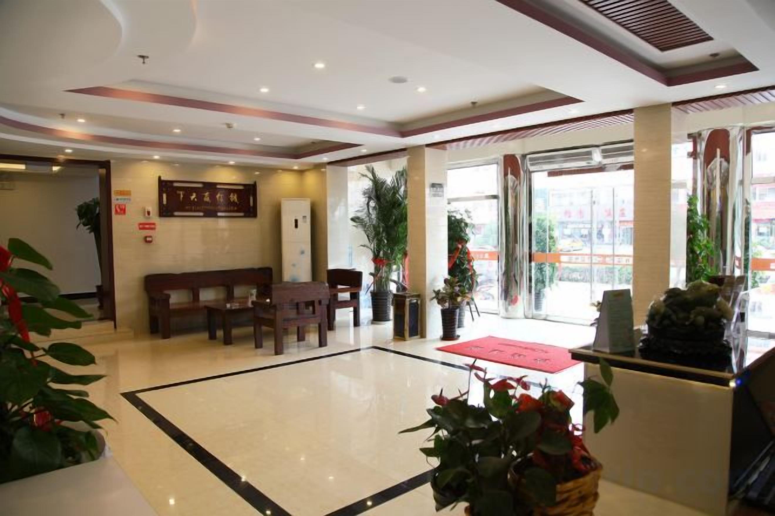 A hotel lobby with a reception desk, seating area, and large windows.