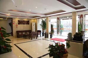 Un hall de hotel con mostrador de recepción, zona de estar y grandes ventanales.