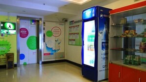 Un vestíbulo con un quiosco de información digital, una vitrina con aperitivos y un mapa en la pared.