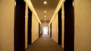 A long, narrow hotel corridor with doors on both sides, leading to a bright room at the end. - Richmond Holiday Hotel (Qinhuangdao Shanhaiguan Laolongtou Resort) (Qinhuangdao)