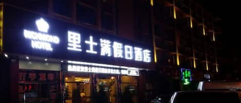 A hotel with a prominent sign, a visible entrance, and a car parked outside.