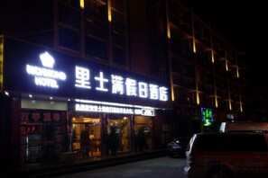 Un hotel con un letrero llamativo, una entrada visible y un coche estacionado afuera.