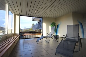 A modern indoor space with a wooden bench, a black lounge chair, and a potted plant. - App. in Haus Feldbergblick with pool, sauna and fitness in Lenzkirch (Lenzkirch)