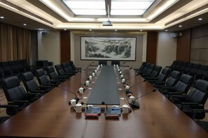 A conference room with a long table, chairs, and a projector screen. - Chiping Hotel (Liaocheng)