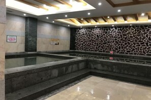 A modern indoor swimming pool with a stone wall and a sign indicating a no swimming zone. - Chiping Hotel (Liaocheng)