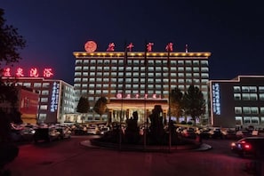 A multi-story hotel with a prominent entrance and a parking lot in front. - Chiping Hotel (Liaocheng)