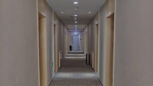 A long, narrow hallway with a patterned carpet, light-colored walls, and a series of doors on one side. - Chiping Hotel (Liaocheng)