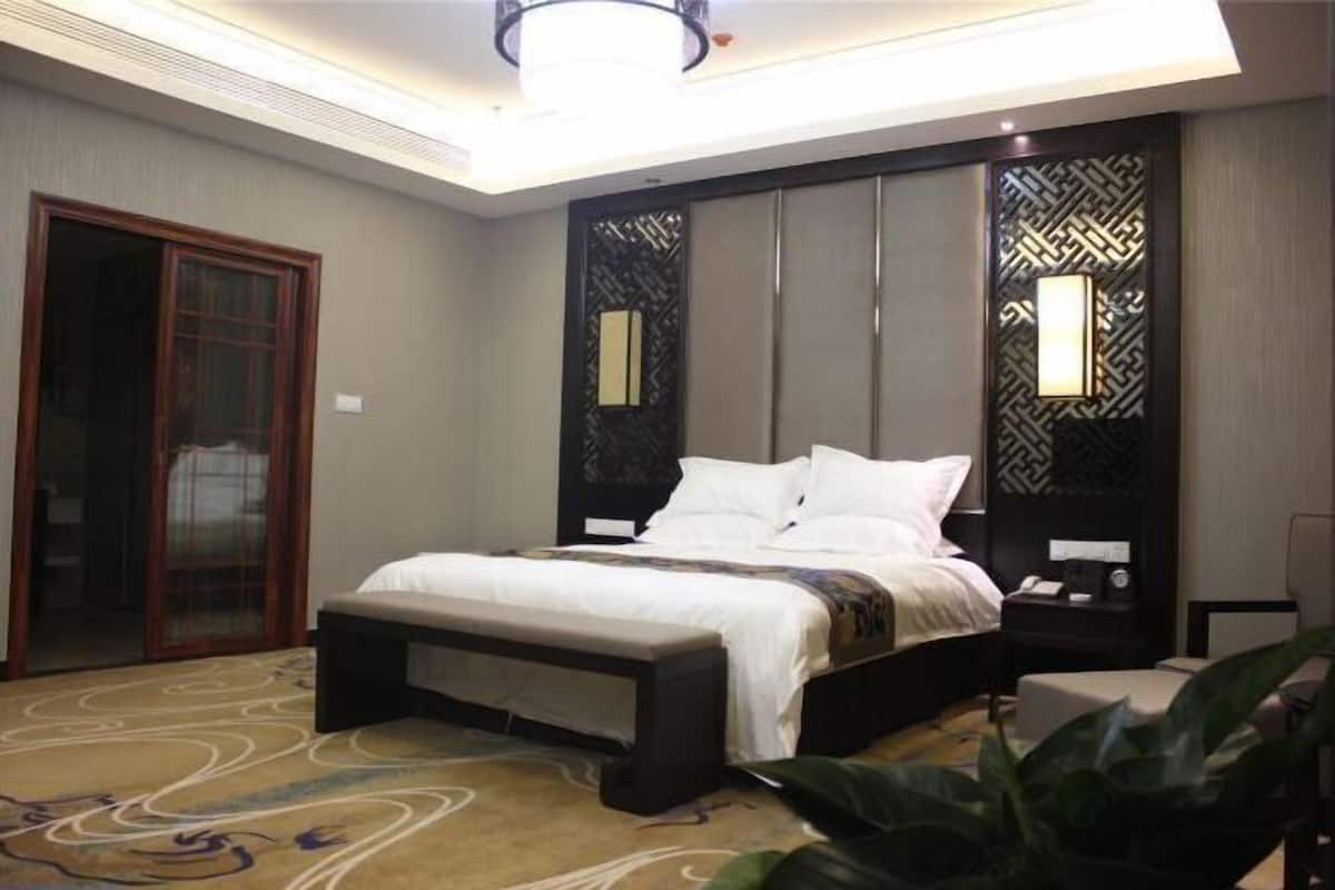 A hotel room with a bed, bedside tables, a nightstand, a large window, and a sliding door.