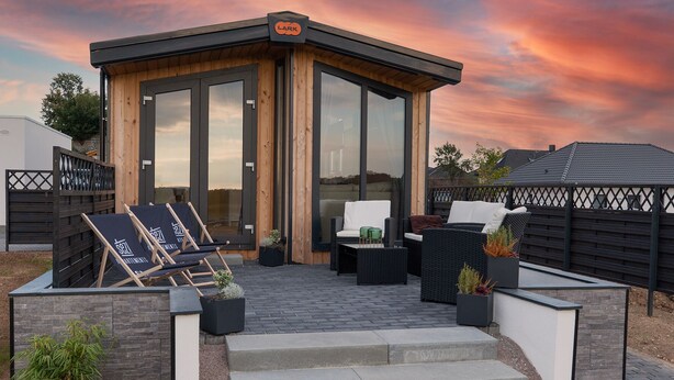 A modern outdoor seating area with a wooden structure, a glass door, and a sign reading "LARK".