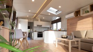 A modern, open-plan living area with a kitchen, dining space, and a sofa.