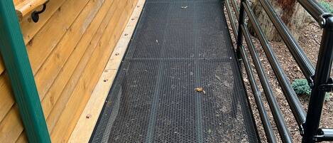 Een houten gebouw met een metalen hellingbaan naar een deur.