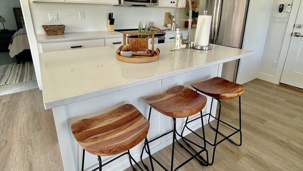 A modern kitchen with white cabinets, a stainless steel refrigerator, a microwave, and a wooden island with bar stools. - CASITA RETREAT APT: full kitchen, Sleeps 4, near Sand Hollow, Zions, & St George (Hurricane)