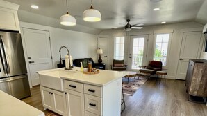 A spacious kitchen with white cabinetry, a central island, pendant lighting, and a ceiling fan. - CASITA RETREAT APT: full kitchen, Sleeps 4, near Sand Hollow, Zions, & St George (Hurricane)
