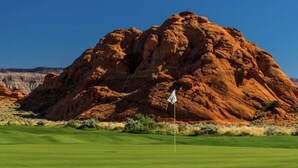 A golf course with a flagstick in the foreground and a large red rock formation in the background. - CASITA RETREAT APT: full kitchen, Sleeps 4, near Sand Hollow, Zions, & St George (Hurricane)
