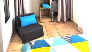 Ein gemütlicher Raum mit Bett, einer kleinen Couch, einem Kleiderschrank und Fliesenboden.