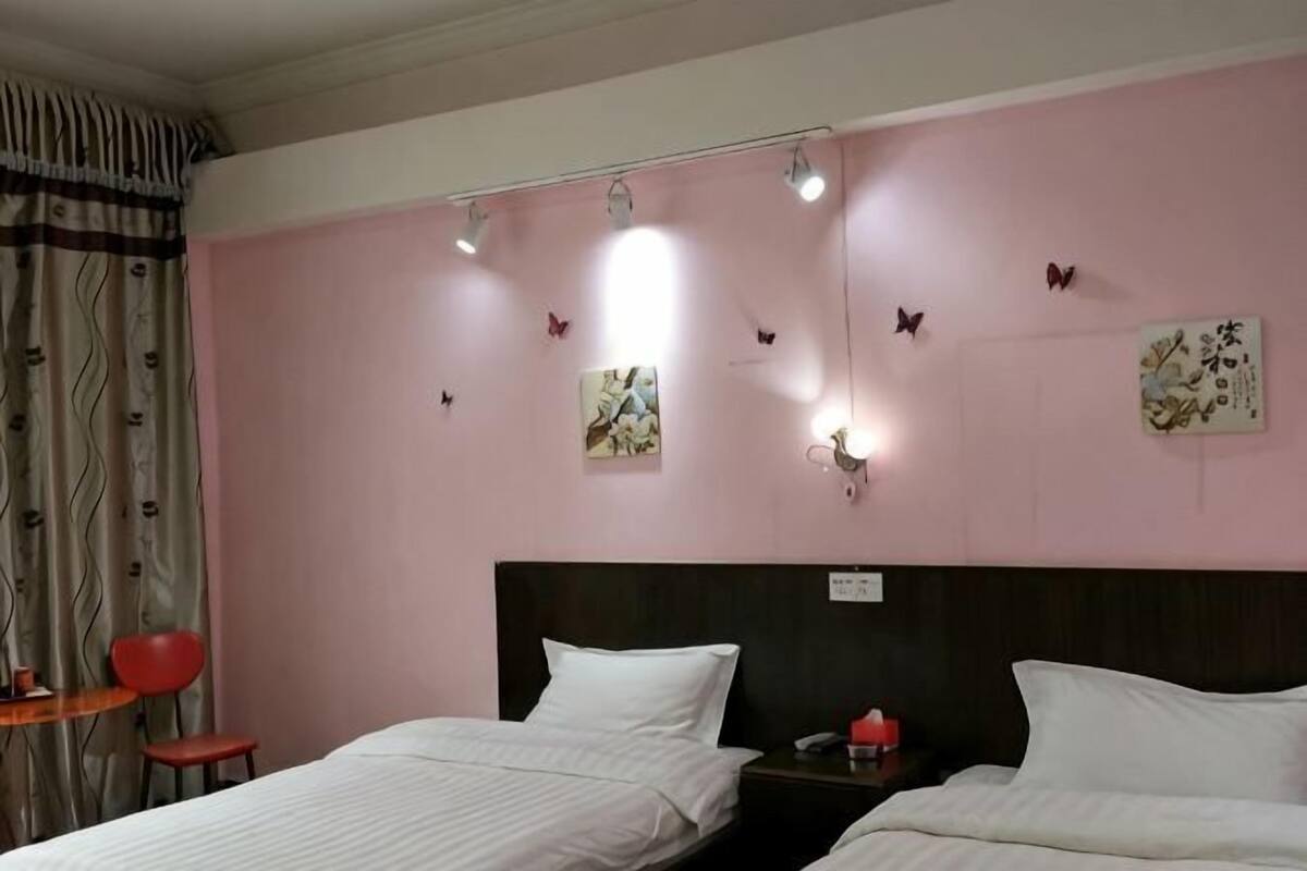 Habitación de hotel con dos camas, cabeceros, adornos en la pared y una mesita de noche.