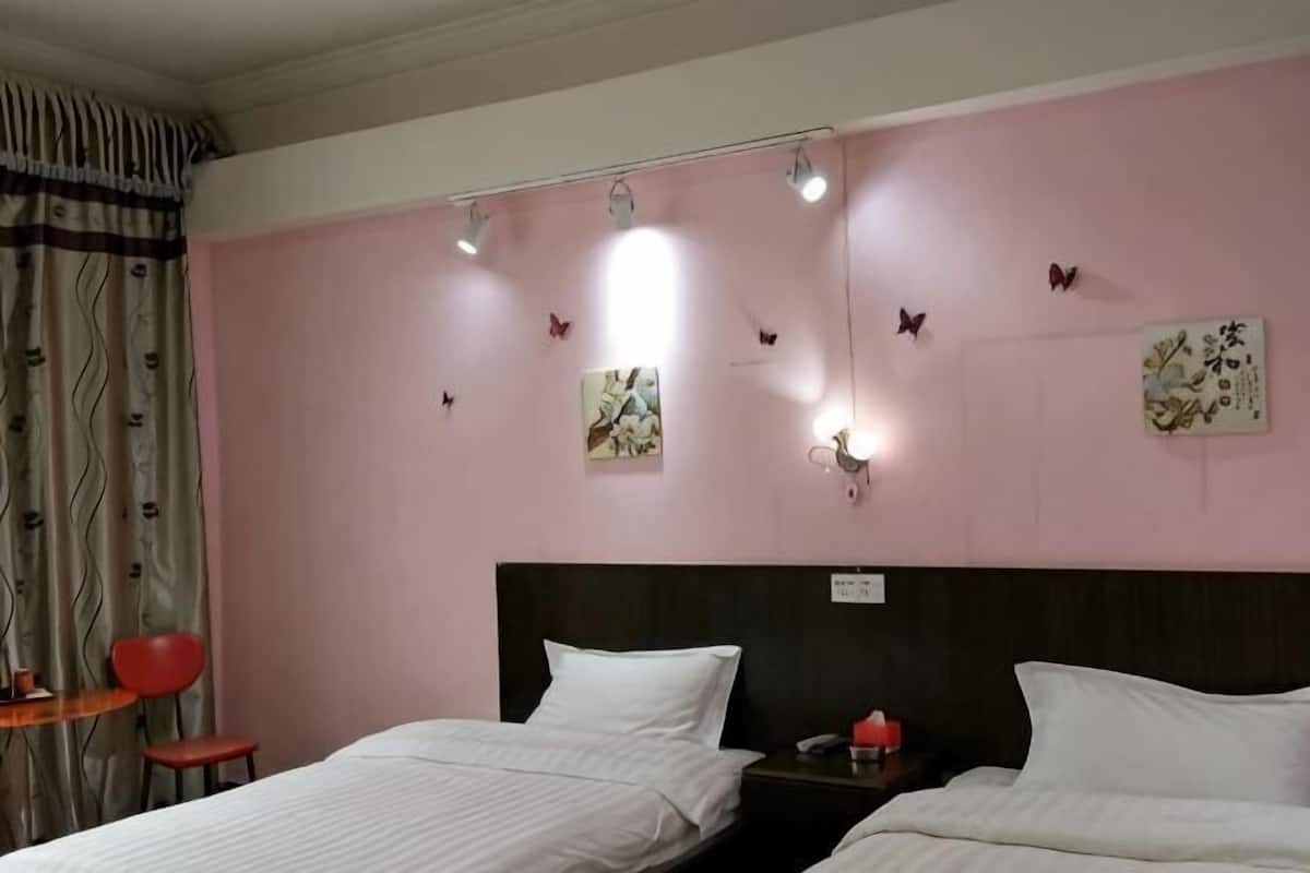 Une chambre d’hôtel avec deux lits, une tête de lit, des éléments de décoration murale et une table de chevet.