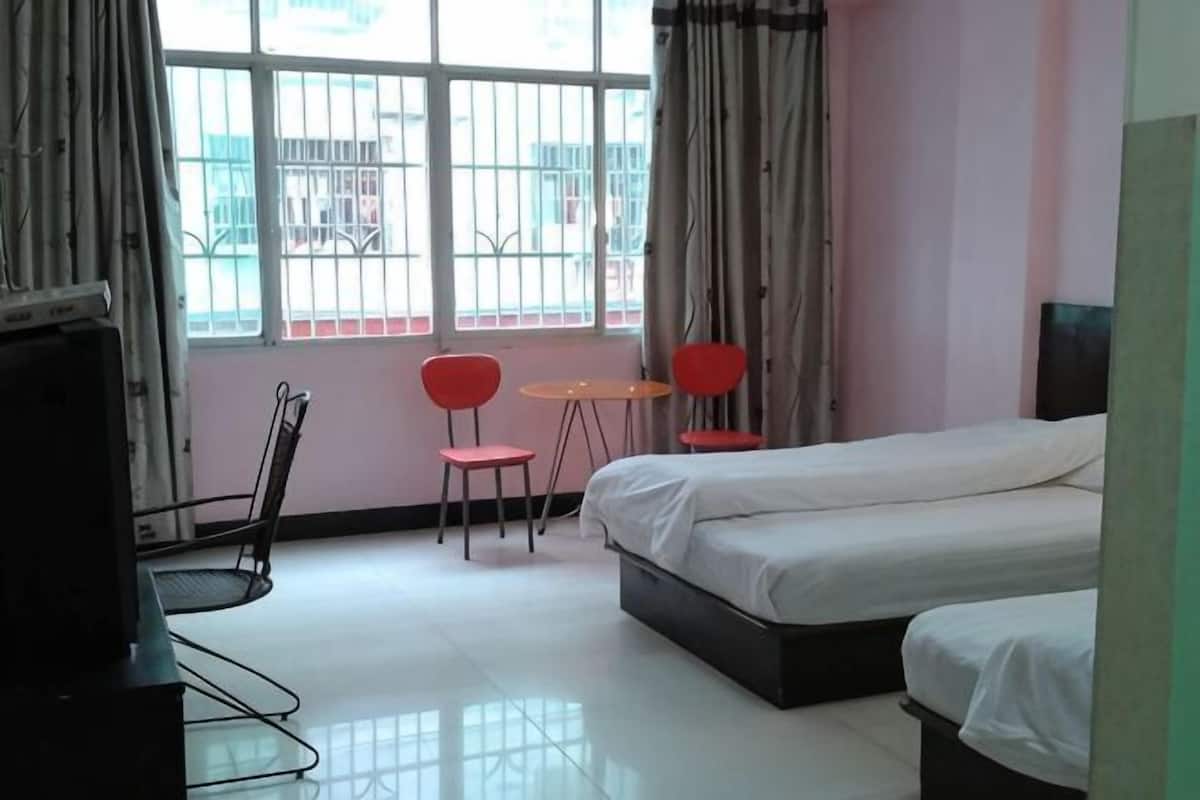 Une chambre dâhĂŽtel avec un lit, deux chaises rouges, une petite table et un tĂ©lĂ©viseur.