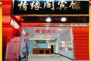 L’entrée d’un hôtel, avec un comptoir d’accueil, une enseigne et une façade rouge.