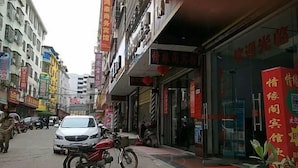 Une vue de rue avec un bâtiment dont la façade est en grande partie constituée d’une vitrine et qui arbore une enseigne rouge.