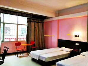 Two single beds with white bedding, a small table, and a chair for dining or working.