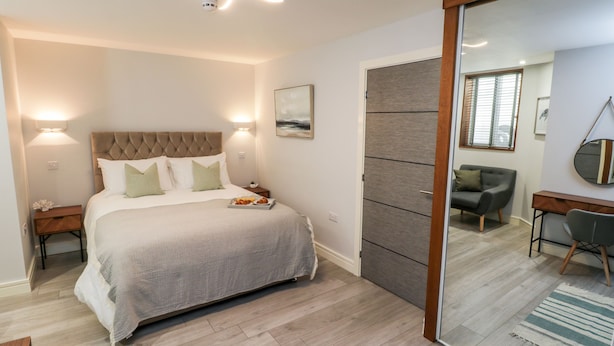 A modern bedroom with a large bed, bedside tables, a desk, and a chair. - North Bay Retreat (Scarborough)