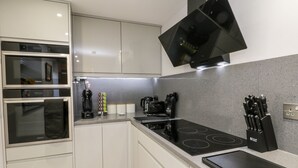 A modern kitchen with built-in ovens, a stovetop, and a range hood. - North Bay Retreat (Scarborough)