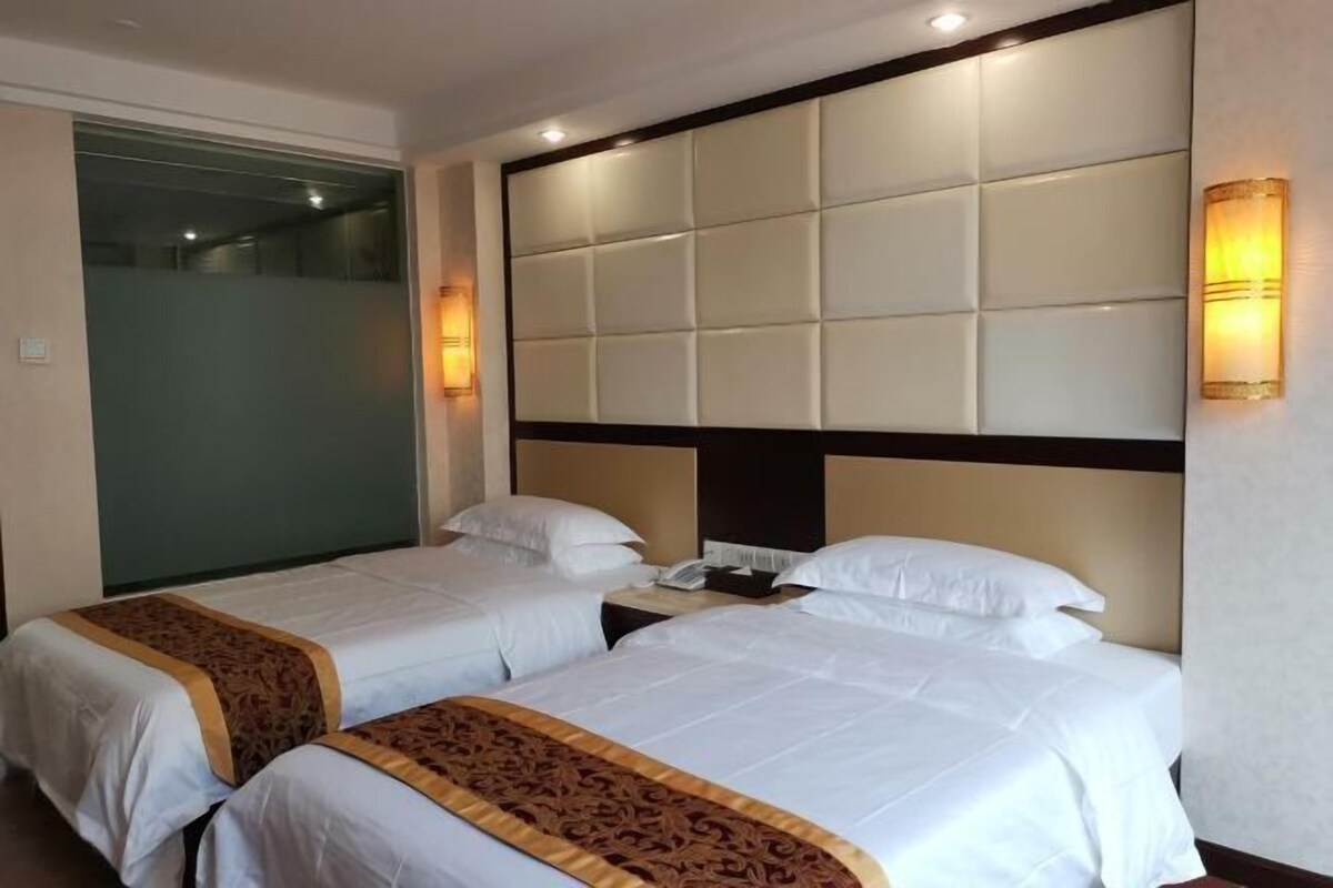 A hotel room with two beds, a padded headboard, bedside lamps, and a telephone on the nightstand.