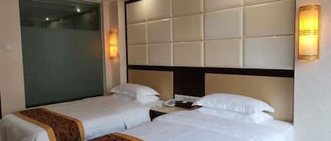 A hotel room with two beds, a padded headboard, bedside lamps, and a telephone on the nightstand.