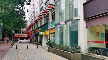 Una calle urbana con comercios, una acera y un coche estacionado.