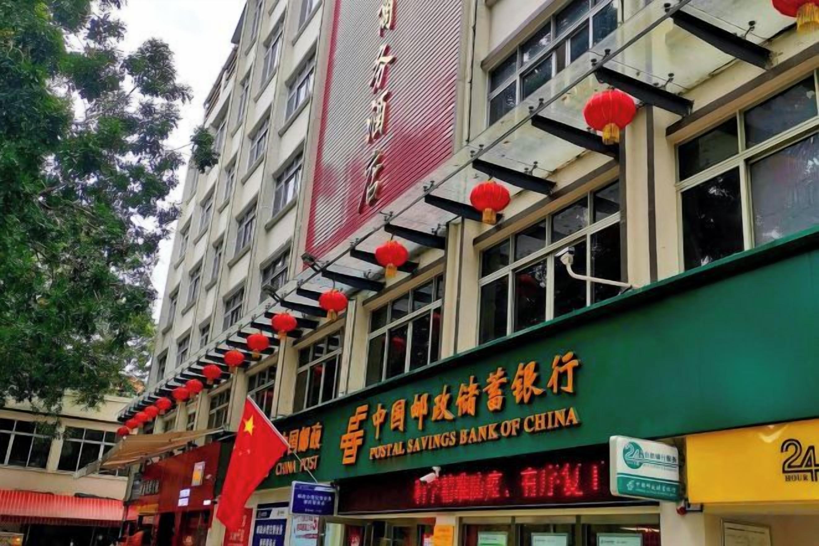 A multi-story building with a prominent sign for a bank and a visible flag.
