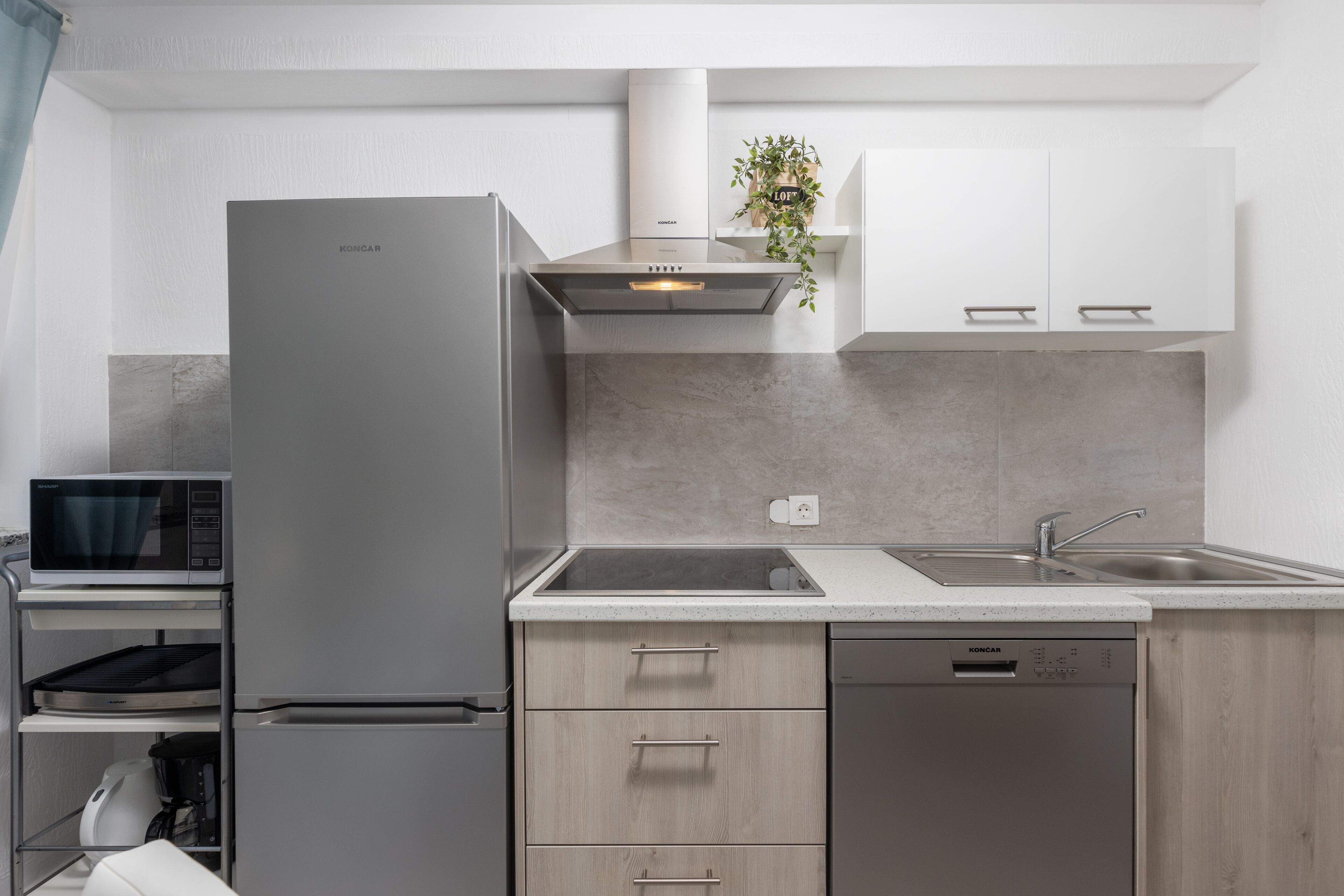 A modern kitchen with a built-in microwave, a stainless steel refrigerator, and a dishwasher.