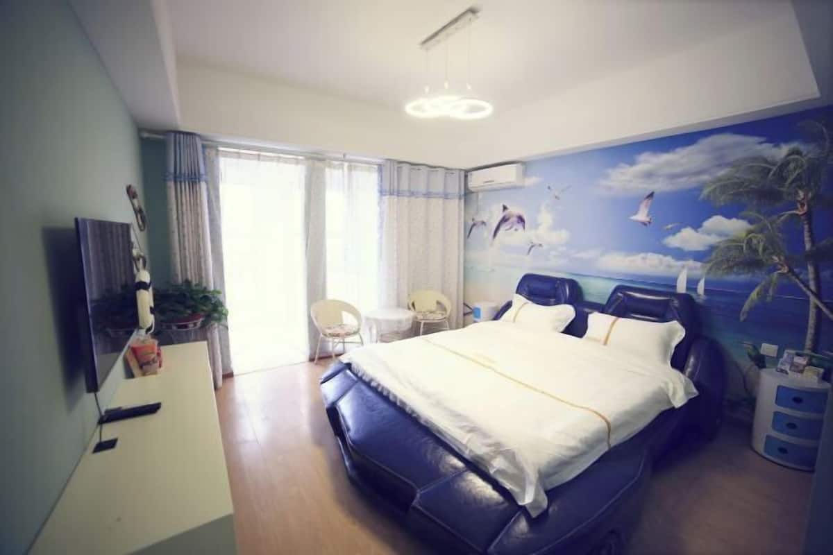 A bedroom with a bed, a desk, a chair, and a wall mural.
